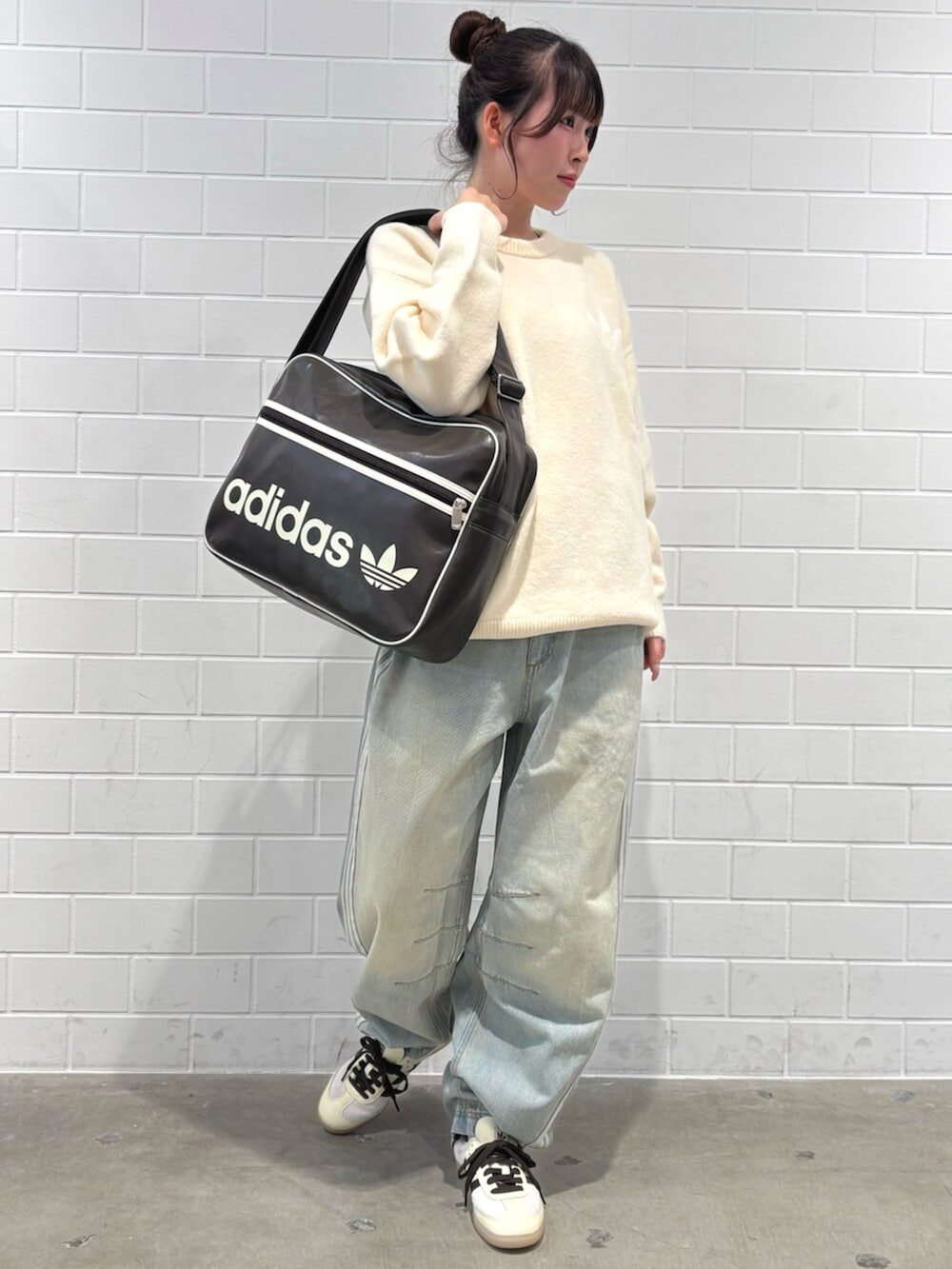 ブルー系のデニムパンツ、ホワイト系のニット/セーター、ブラウン系のバッグを着用したレディースの秋コーディネートの3枚目の写真