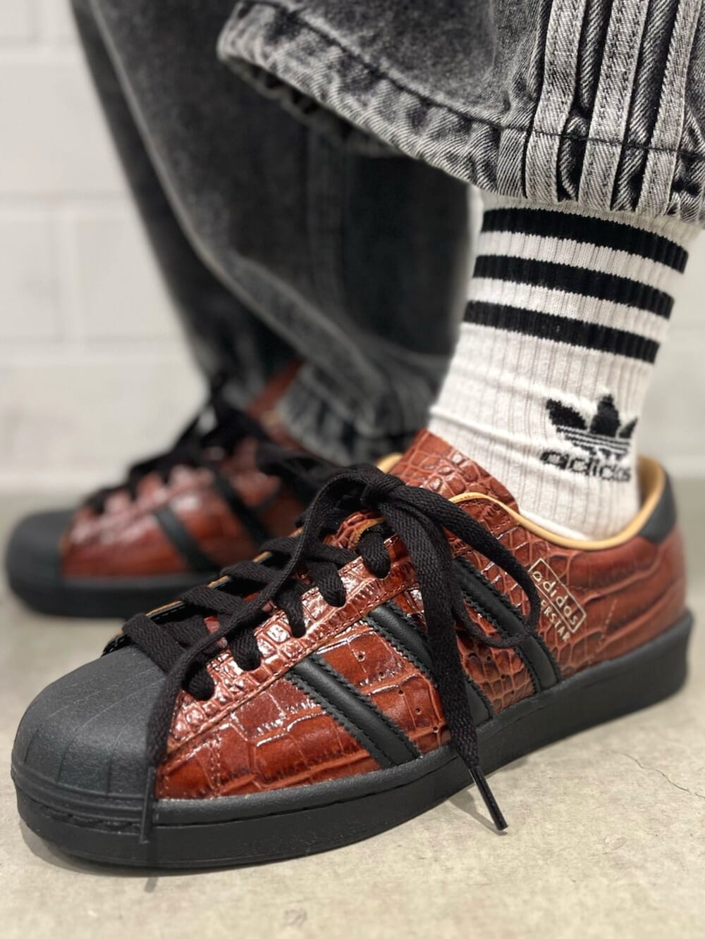 ブラック系のデニムパンツ、ブラウン系のシューズ、レッド系のジャージを着用したレディースの秋コーディネートの6枚目の写真