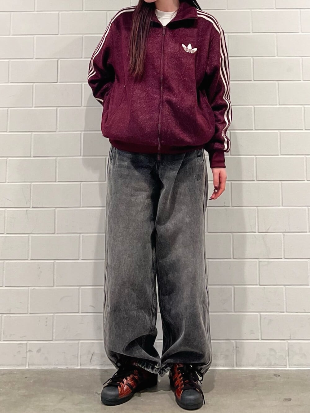 ブラック系のデニムパンツ、ブラウン系のシューズ、レッド系のジャージを着用したレディースの秋コーディネートの2枚目の写真