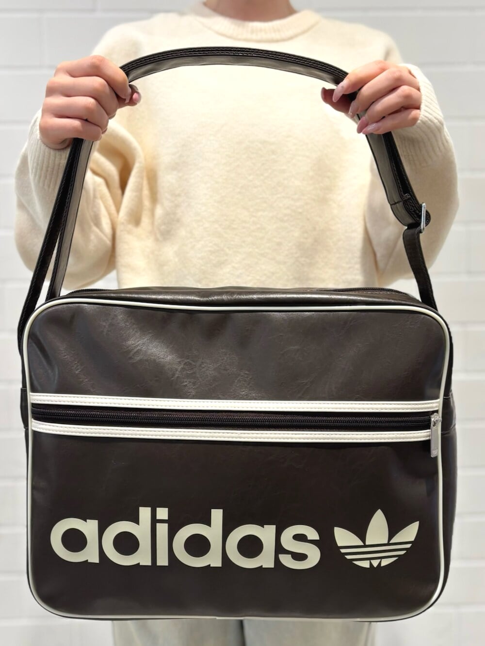 ブルー系のデニムパンツ、ホワイト系のニット/セーター、ブラウン系のバッグを着用したレディースの秋コーディネートの5枚目の写真