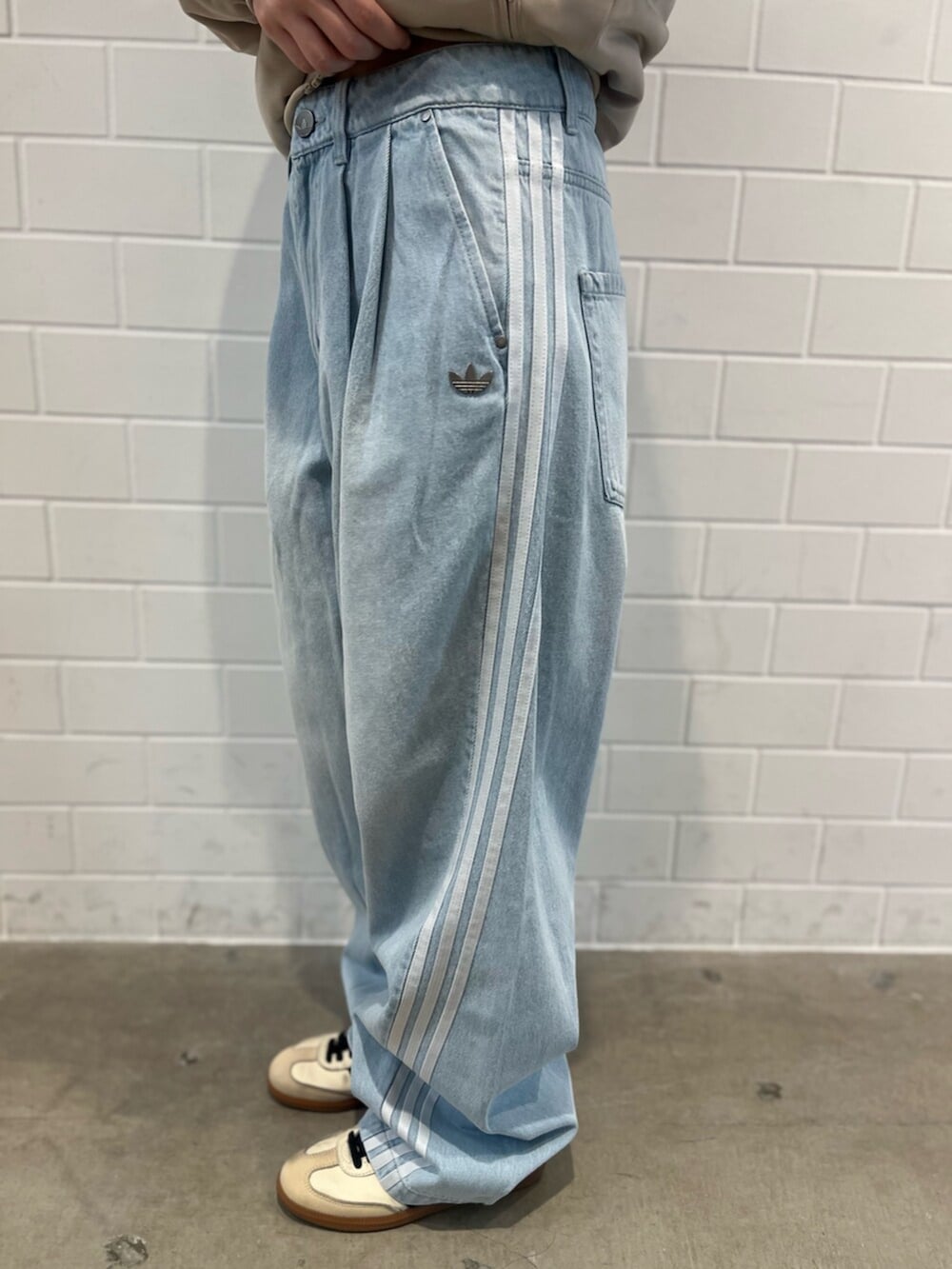 ベージュ系のスニーカー、ブルー系のデニムパンツ、グリーン系のジャージを着用したレディースの春コーディネートの5枚目の写真