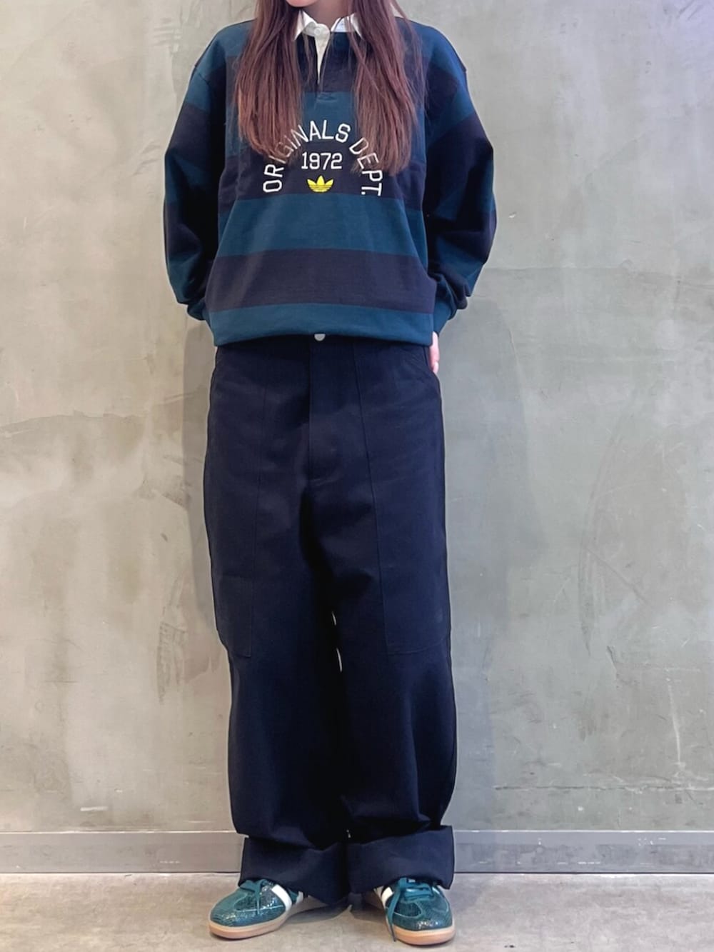 ブラック系のポロシャツ、グリーン系のスニーカー、グリーン系のキャップを着用したレディースの秋コーディネートの2枚目の写真