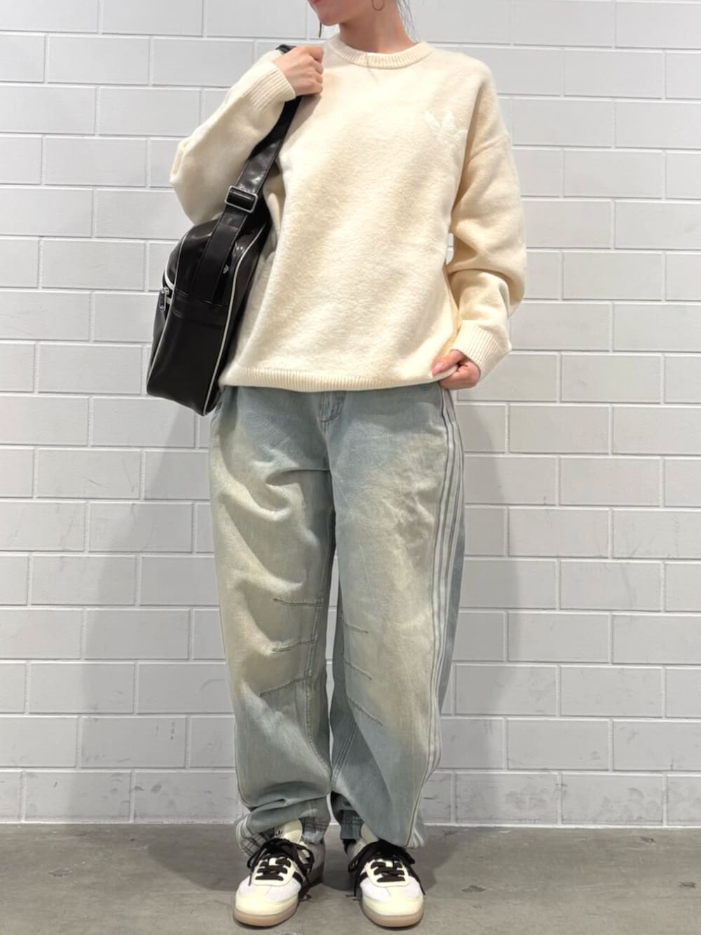 ブルー系のデニムパンツ、ホワイト系のニット/セーター、ブラウン系のバッグを着用したレディースの秋コーディネートの2枚目の写真