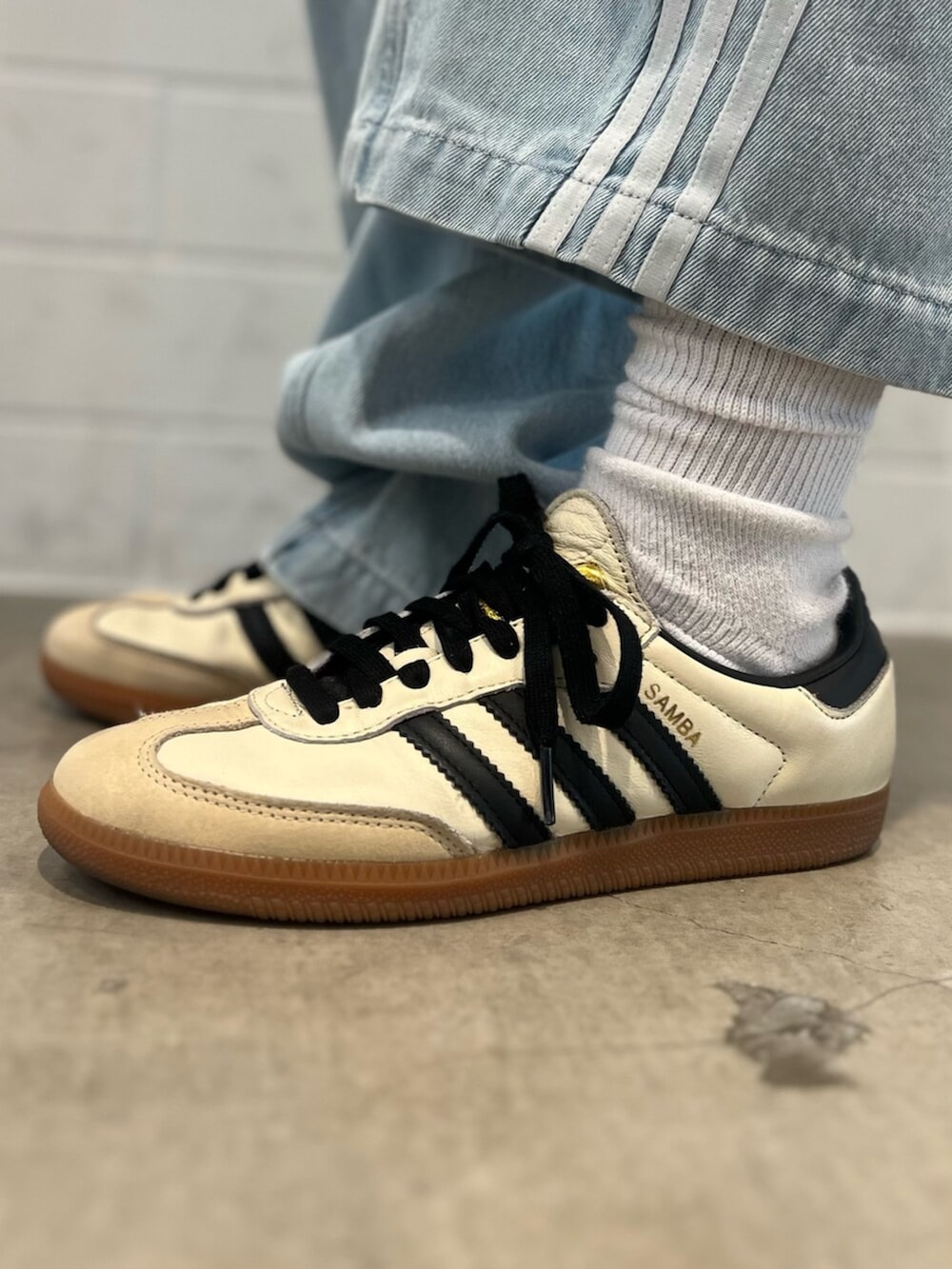 ベージュ系のスニーカー、ブルー系のデニムパンツ、グリーン系のジャージを着用したレディースの春コーディネートの6枚目の写真