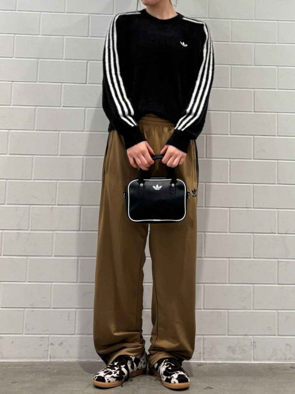 ブラック系のショルダーバッグ、ブラウン系のスニーカー、ブラック系のニット/セーターを着用したレディースの秋コーディネートの2枚目の写真