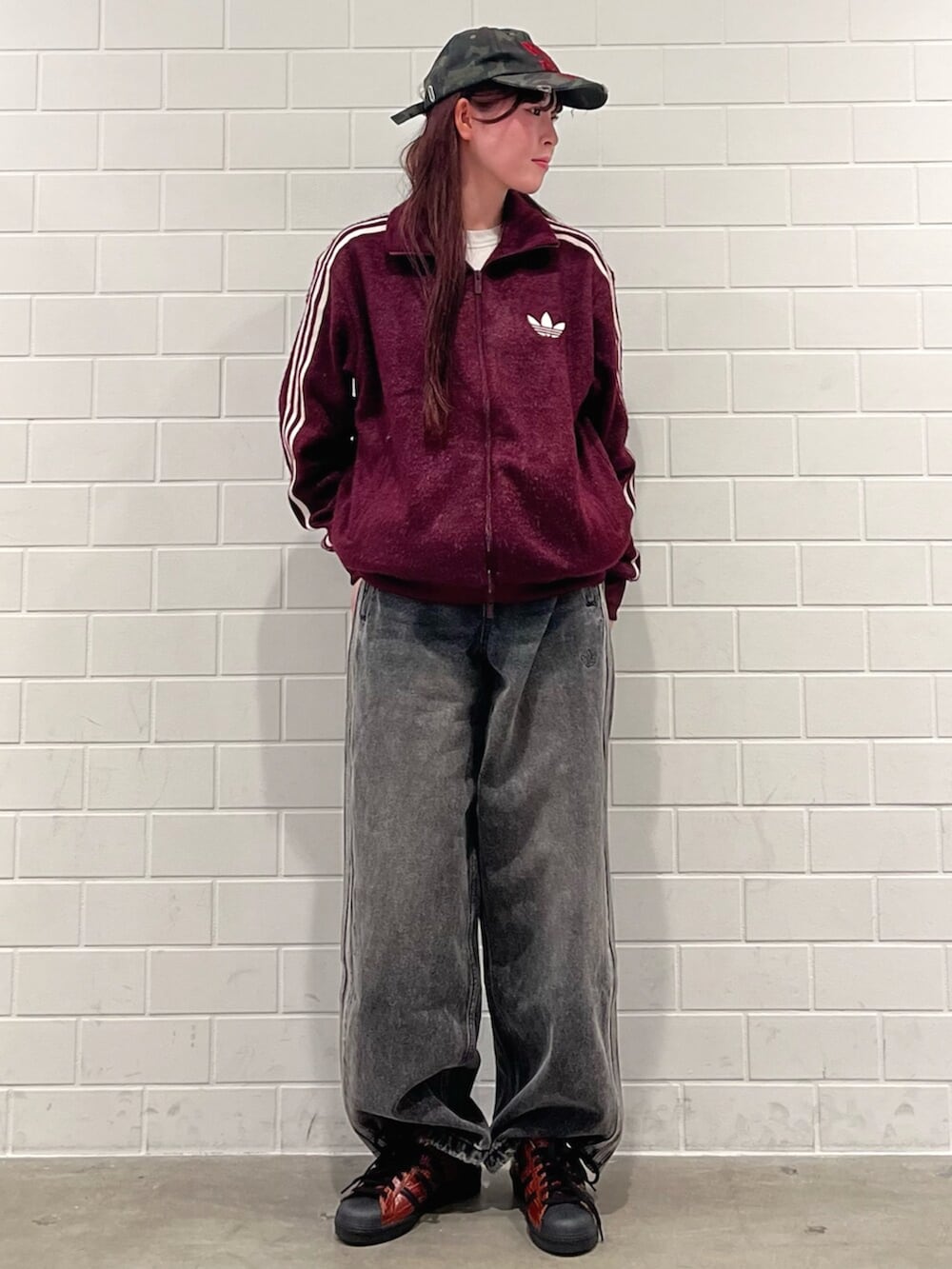 ブラック系のデニムパンツ、ブラウン系のシューズ、レッド系のジャージを着用したレディースの秋コーディネートの3枚目の写真