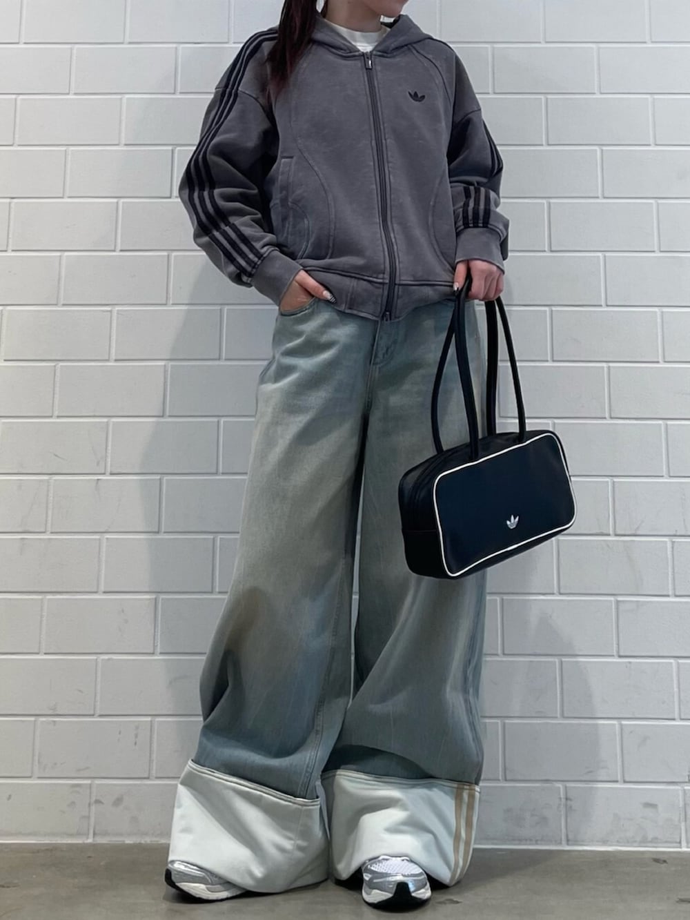 ブラック系のショルダーバッグ、ブルー系のデニムパンツ、グレー系のパーカーを着用したレディースの冬コーディネートの2枚目の写真