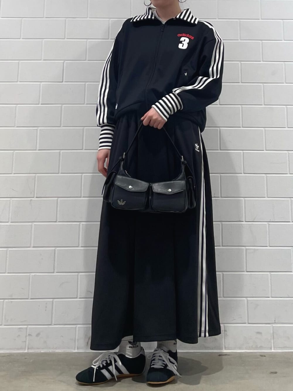 ブラック系のスニーカー、ブラック系のショルダーバッグ、ブラック系のスカートを着用したレディースの冬コーディネートの2枚目の写真