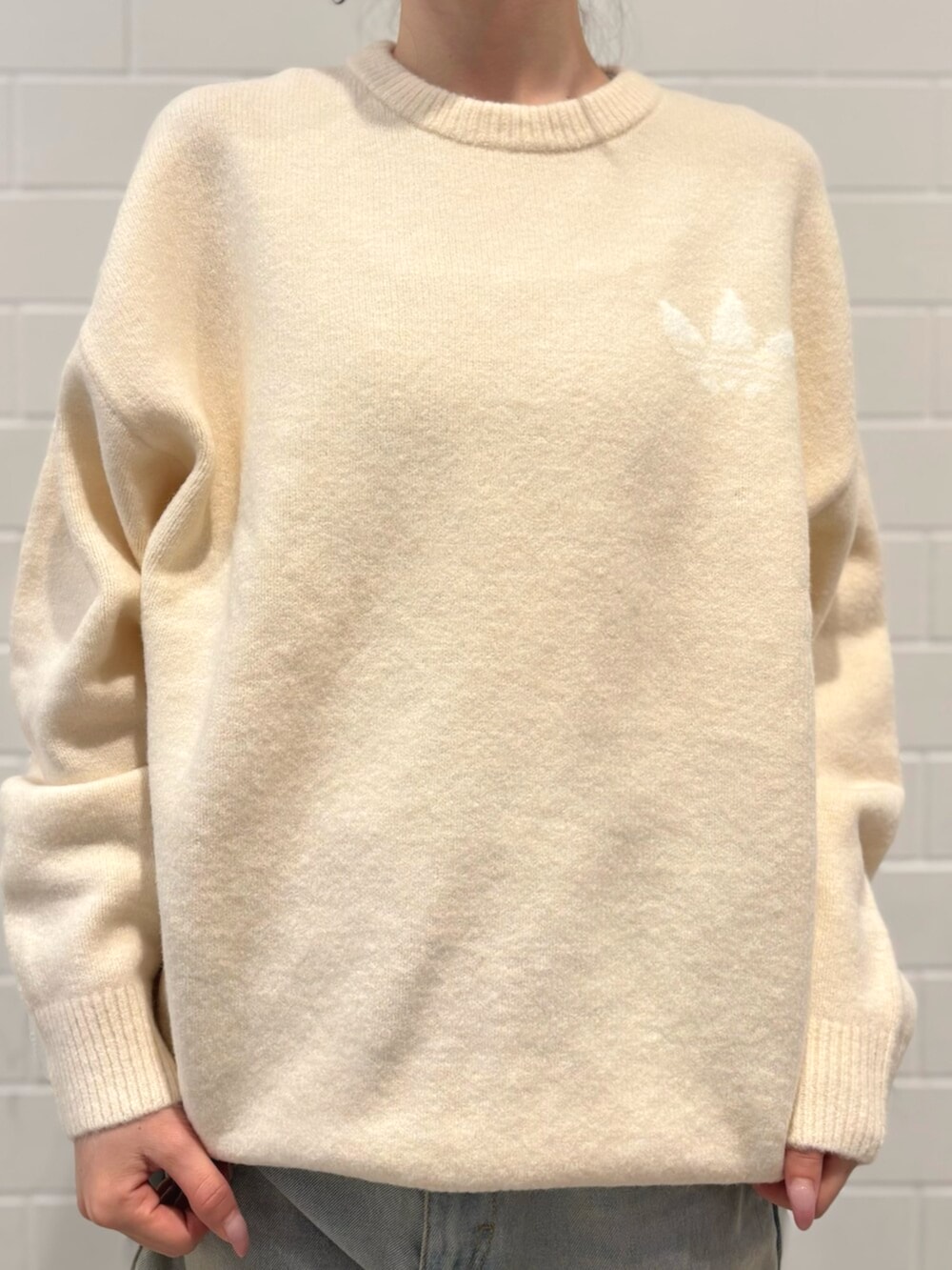 ブルー系のデニムパンツ、ホワイト系のニット/セーター、ブラウン系のバッグを着用したレディースの秋コーディネートの4枚目の写真