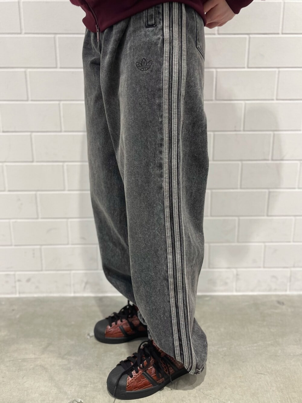 ブラック系のデニムパンツ、ブラウン系のシューズ、レッド系のジャージを着用したレディースの秋コーディネートの5枚目の写真