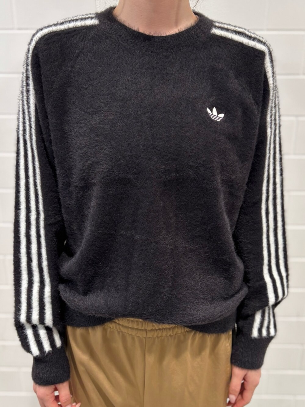 ブラック系のショルダーバッグ、ブラウン系のスニーカー、ブラック系のニット/セーターを着用したレディースの秋コーディネートの3枚目の写真