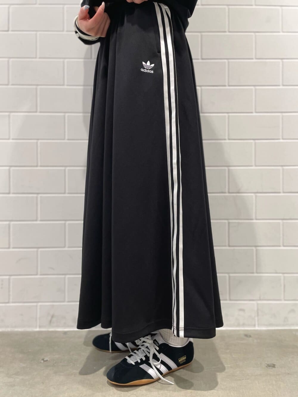 ブラック系のスニーカー、ブラック系のショルダーバッグ、ブラック系のスカートを着用したレディースの冬コーディネートの5枚目の写真