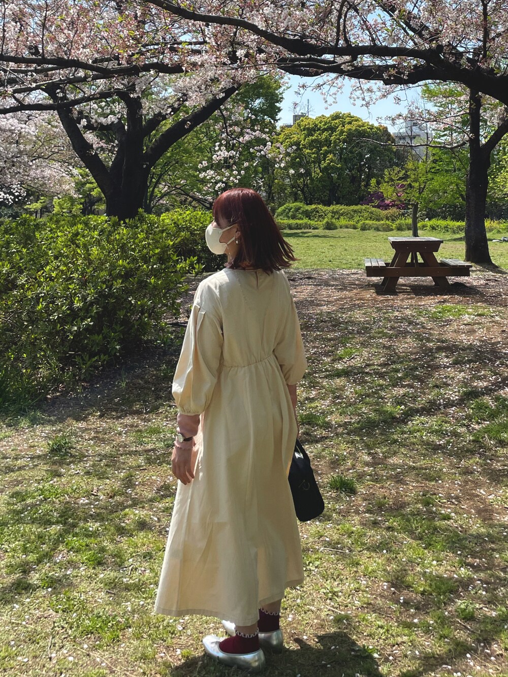 ブラック系のハンドバッグ、ホワイト系のワンピースを着用したレディースの春コーディネートの2枚目の写真