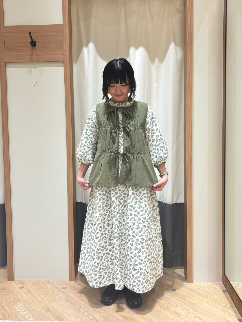 ホワイト系のワンピース、グリーン系のベストを着用したレディースの夏コーディネートの2枚目の写真