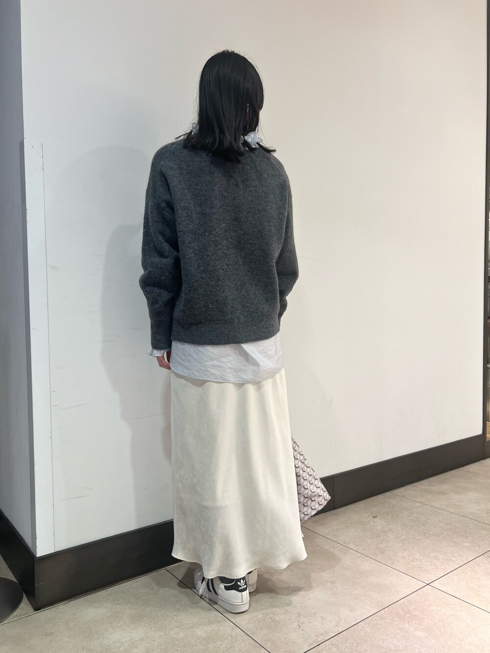 グレー系のニット/セーター、ブルー系のシャツ/ブラウス、ブルー系のショルダーバッグを着用したレディースの冬コーディネートの9枚目の写真