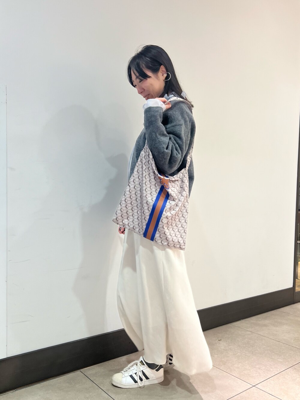 グレー系のニット/セーター、ブルー系のシャツ/ブラウス、ブルー系のショルダーバッグを着用したレディースの冬コーディネートの2枚目の写真