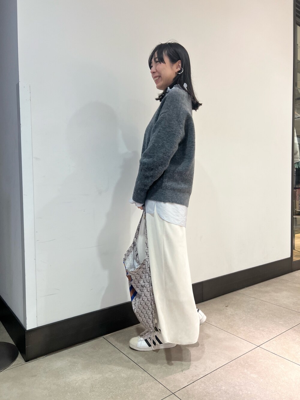 グレー系のニット/セーター、ブルー系のシャツ/ブラウス、ブルー系のショルダーバッグを着用したレディースの冬コーディネートの5枚目の写真