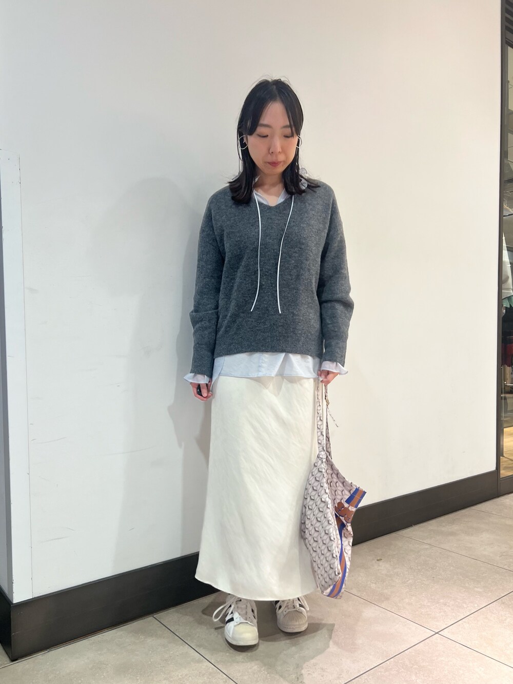 グレー系のニット/セーター、ブルー系のシャツ/ブラウス、ブルー系のショルダーバッグを着用したレディースの冬コーディネートの7枚目の写真