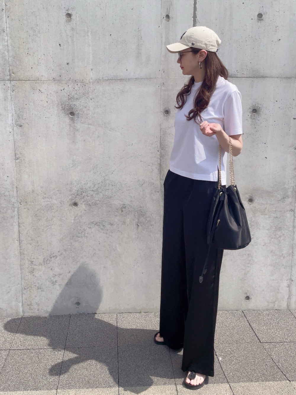 ブラック系のサンダル、ホワイト系のTシャツ/カットソー、ブラック系のパンツを着用したレディースの夏コーディネートの2枚目の写真