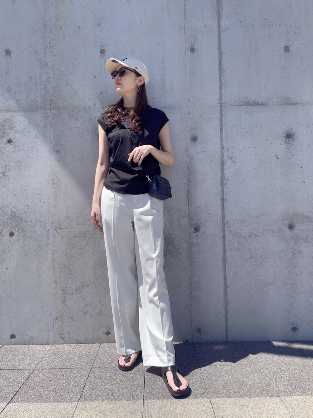 ホワイト系のパンツ、ブラック系のサンダル、ホワイト系のキャップを着用したレディースの夏コーディネートの2枚目の写真
