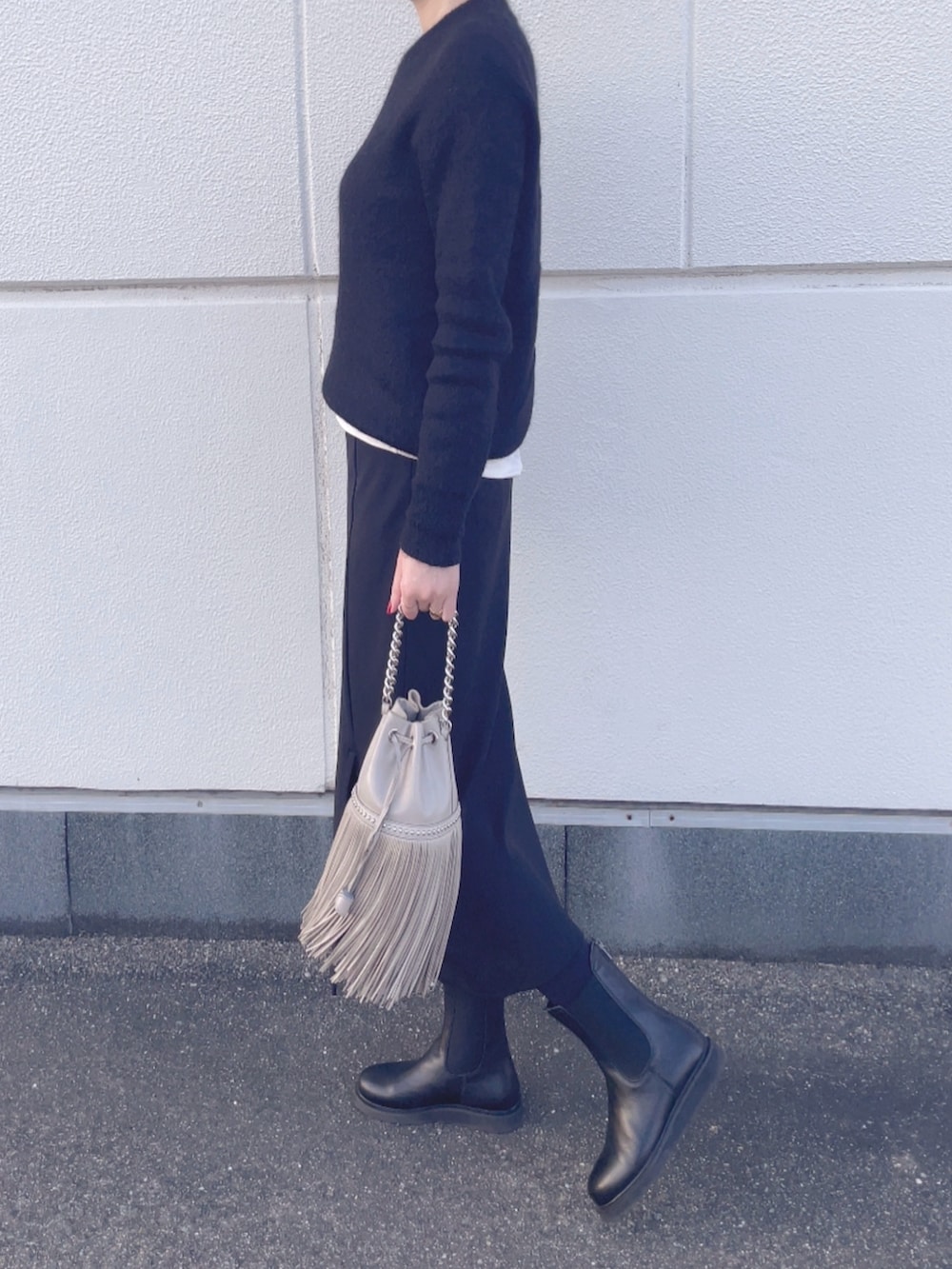 ベージュ系のショルダーバッグ、ブラック系のニット/セーター、ブラック系のスカートを着用したレディースの冬コーディネートの2枚目の写真