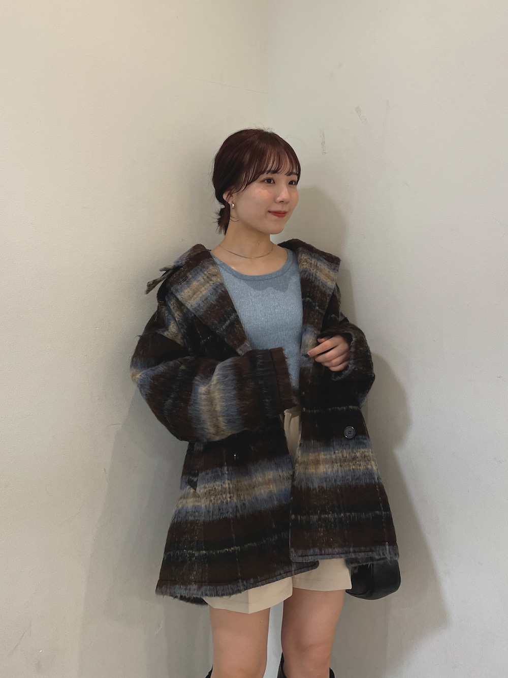 ブルー系のニット/セーター、ブラウン系のその他アウター、ブラック系のブーツを着用したレディースの冬コーディネートの2枚目の写真