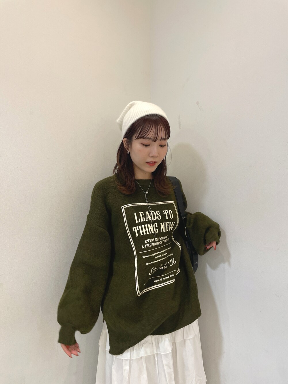 グリーン系のニット/セーター、ホワイト系のスカート、ブラック系のショルダーバッグを着用したレディースの秋コーディネートの4枚目の写真