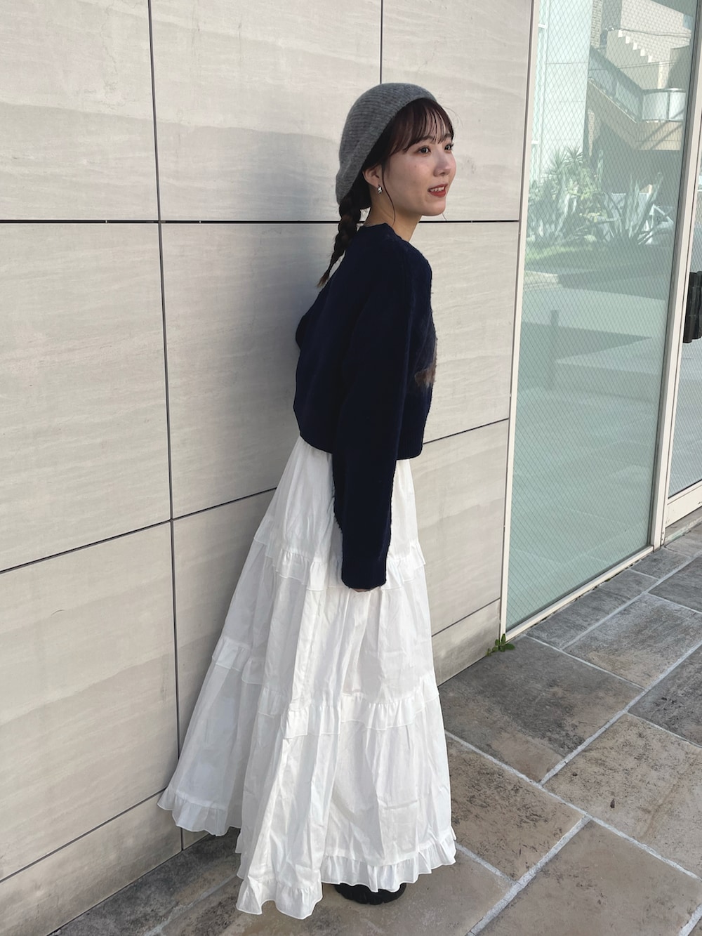 ブルー系のニット/セーター、ホワイト系のスカート、ブラック系のスニーカーを着用したレディースの秋コーディネートの3枚目の写真