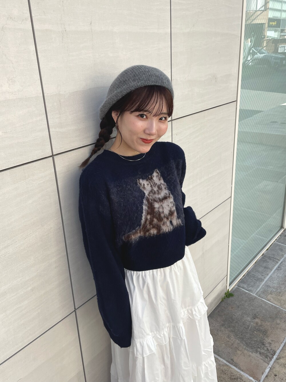 ブルー系のニット/セーター、ホワイト系のスカート、ブラック系のスニーカーを着用したレディースの秋コーディネートの2枚目の写真