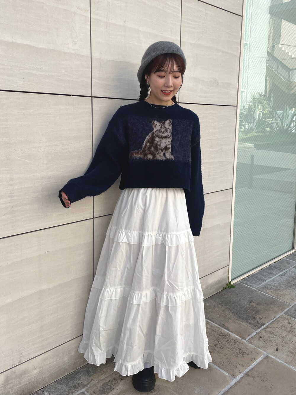 ブルー系のニット/セーター、ホワイト系のスカート、ブラック系のスニーカーを着用したレディースの秋コーディネートの4枚目の写真