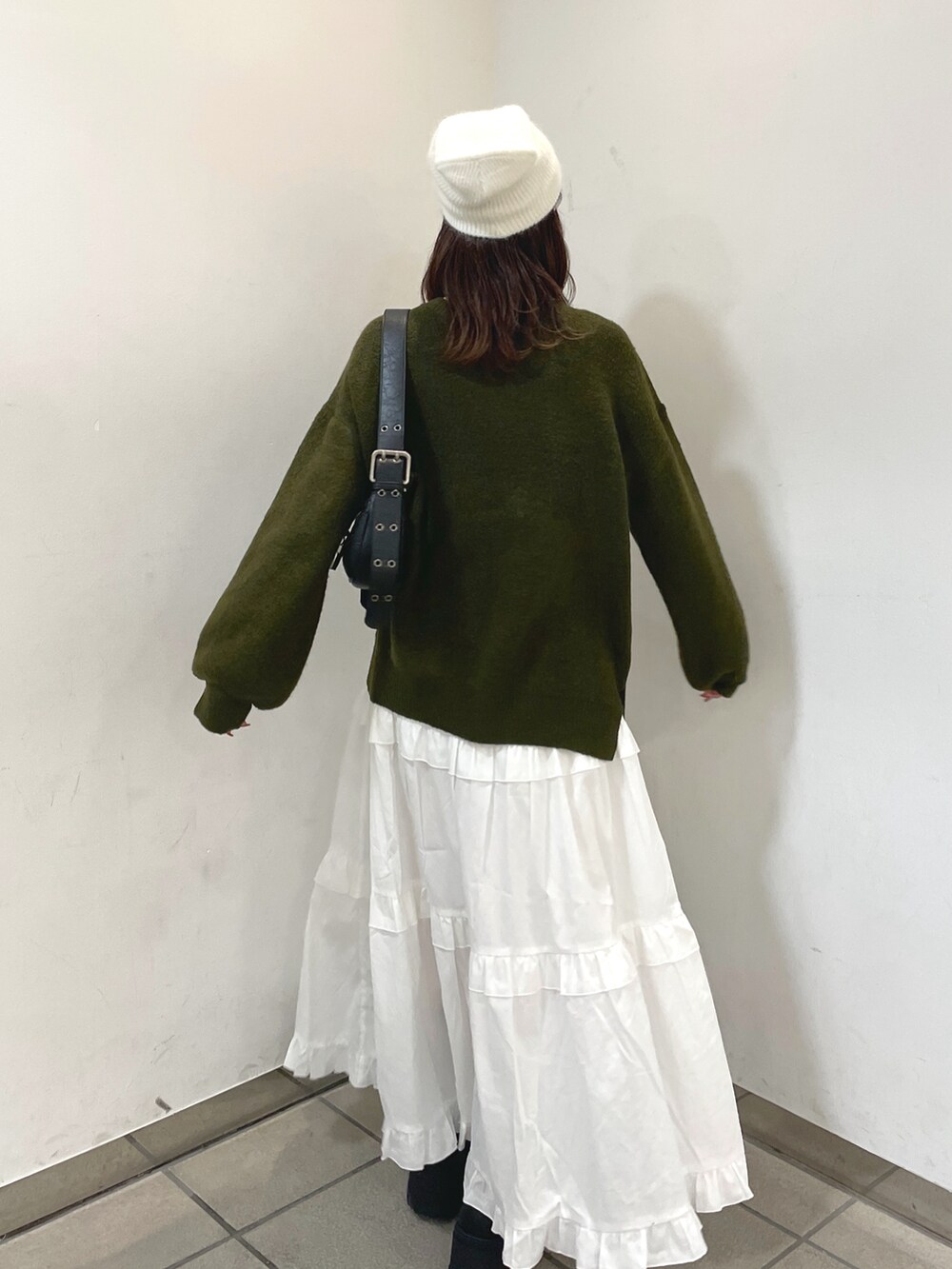 グリーン系のニット/セーター、ホワイト系のスカート、ブラック系のショルダーバッグを着用したレディースの秋コーディネートの3枚目の写真