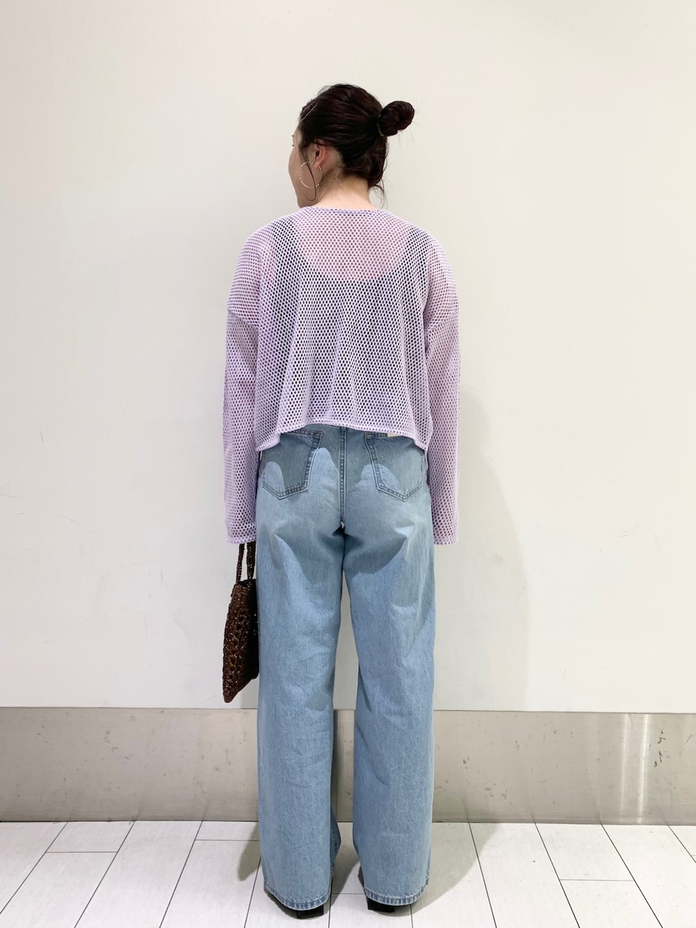 パープル系のカーディガン/ボレロ、ブルー系のデニムパンツ、ブラウン系のショルダーバッグを着用したレディースの春コーディネートの2枚目の写真