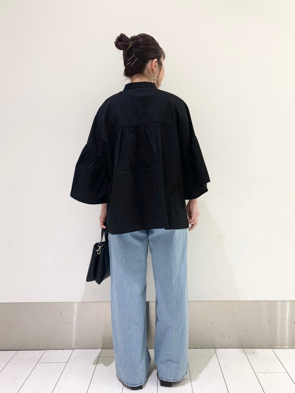 ブラック系のシャツ/ブラウス、ブラック系のショルダーバッグ、ブルー系のデニムパンツを着用したレディースの春コーディネートの2枚目の写真