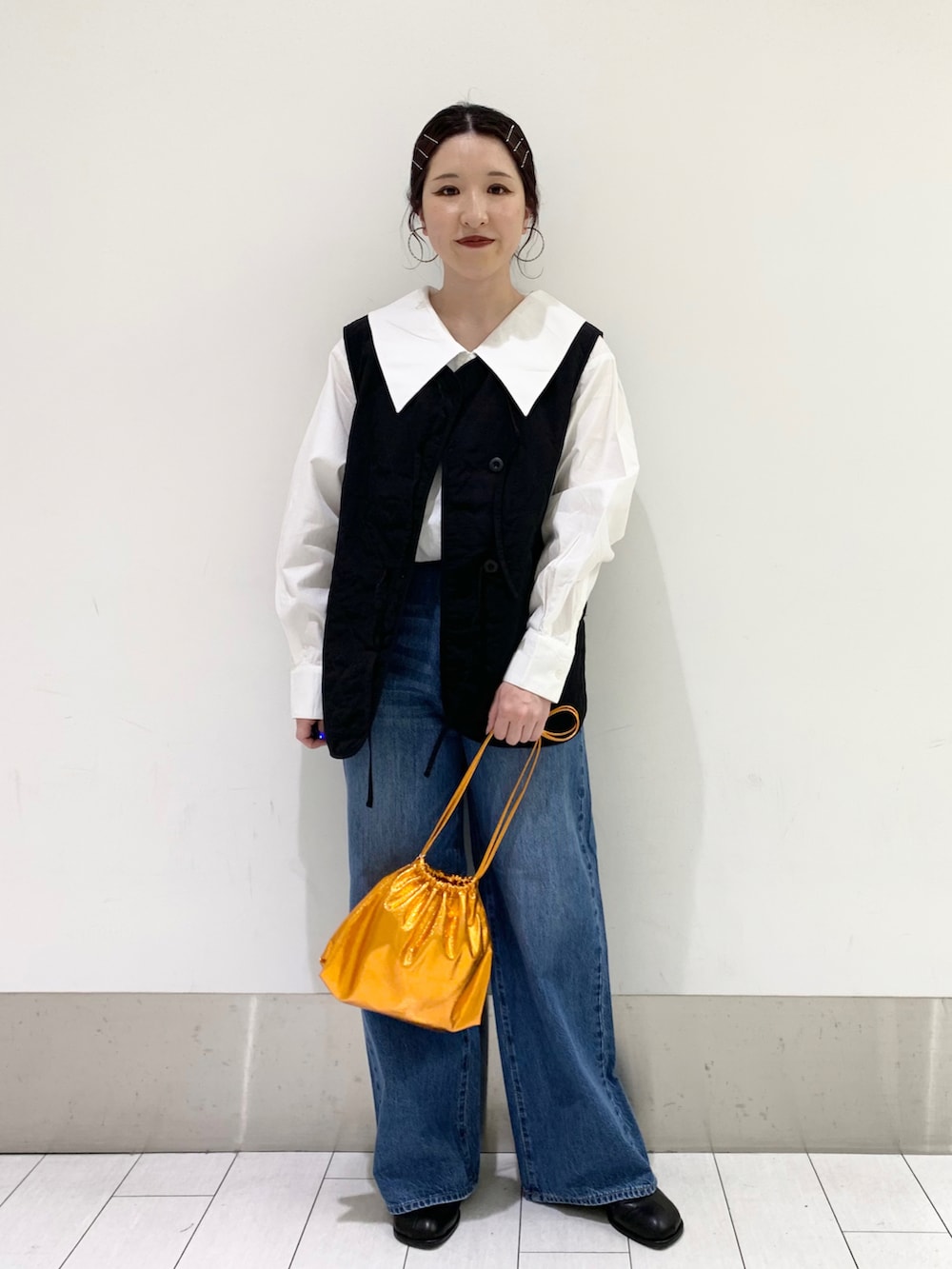 ブルー系のデニムパンツ、オレンジ系のショルダーバッグ、ブラック系のパンプスを着用したレディースの春コーディネートの2枚目の写真