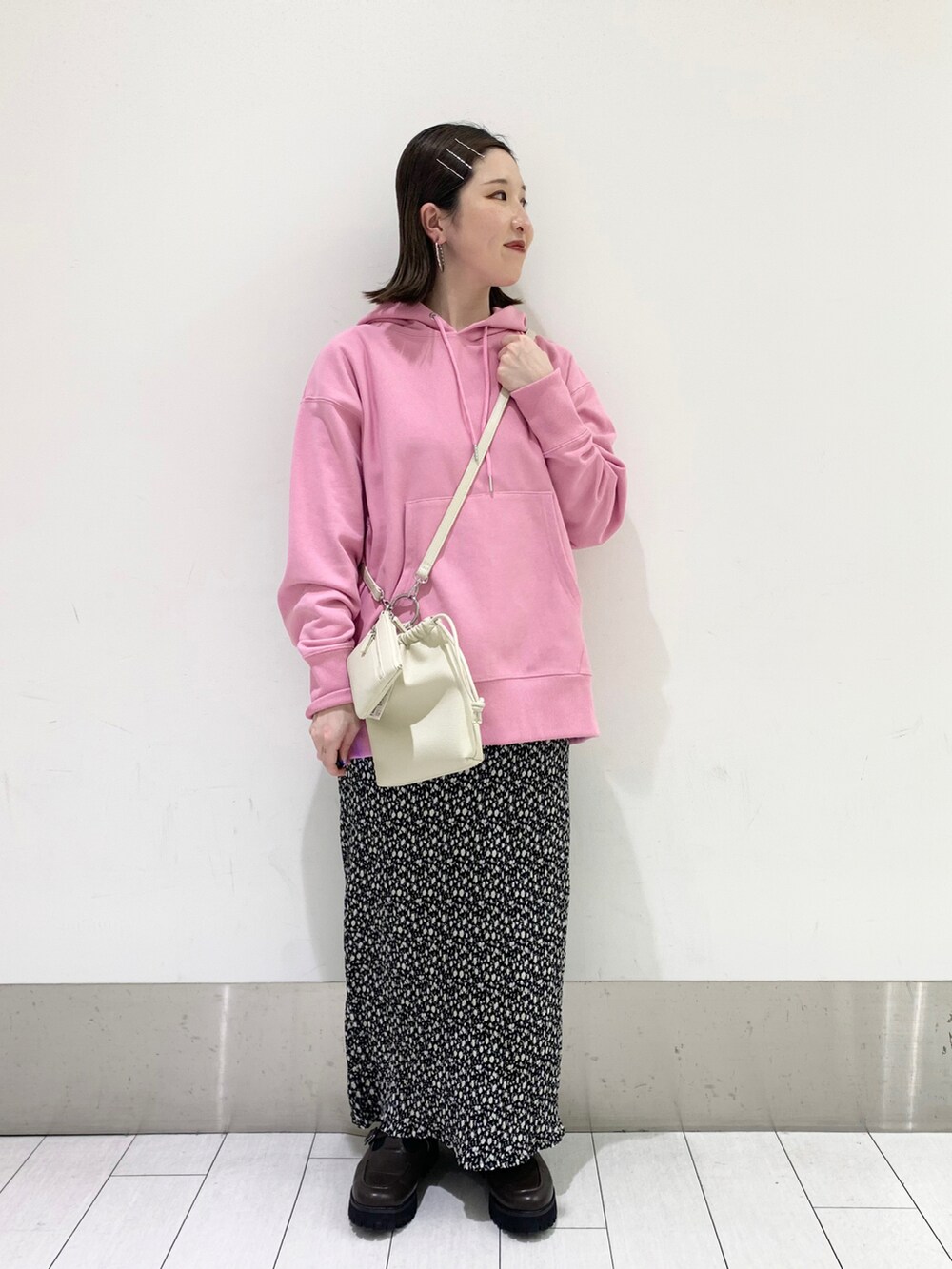 ピンク系のパーカー、ブラック系のスカート、ブラウン系のローファーを着用したレディースの春コーディネートの3枚目の写真