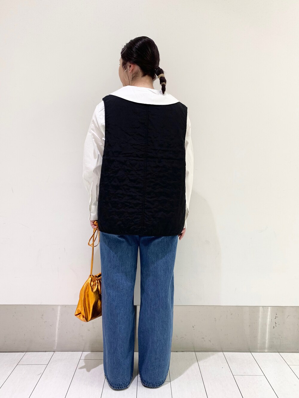 ブルー系のデニムパンツ、オレンジ系のショルダーバッグ、ブラック系のパンプスを着用したレディースの春コーディネートの3枚目の写真