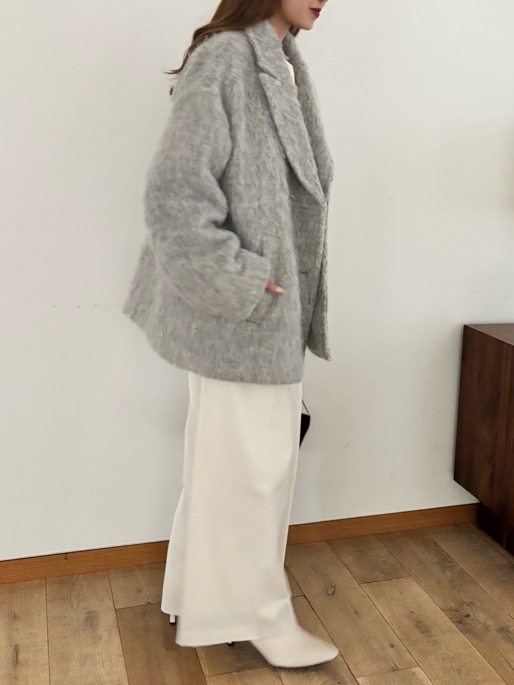 グレー系のピーコート、ホワイト系のスラックス、ブラック系のバッグを着用したレディースの秋コーディネートの3枚目の写真