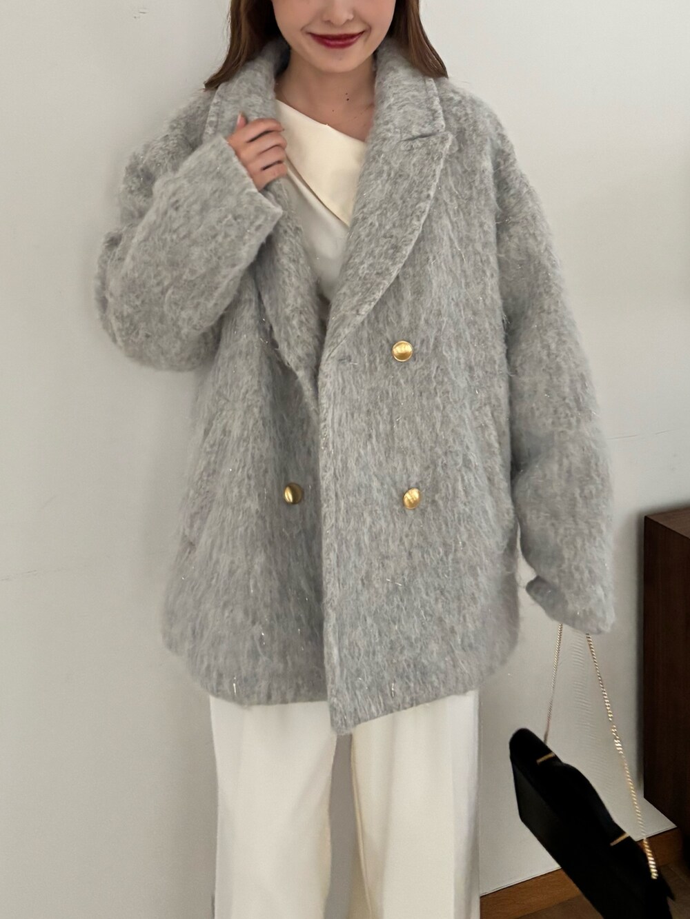 グレー系のピーコート、ホワイト系のスラックス、ブラック系のバッグを着用したレディースの秋コーディネートの6枚目の写真