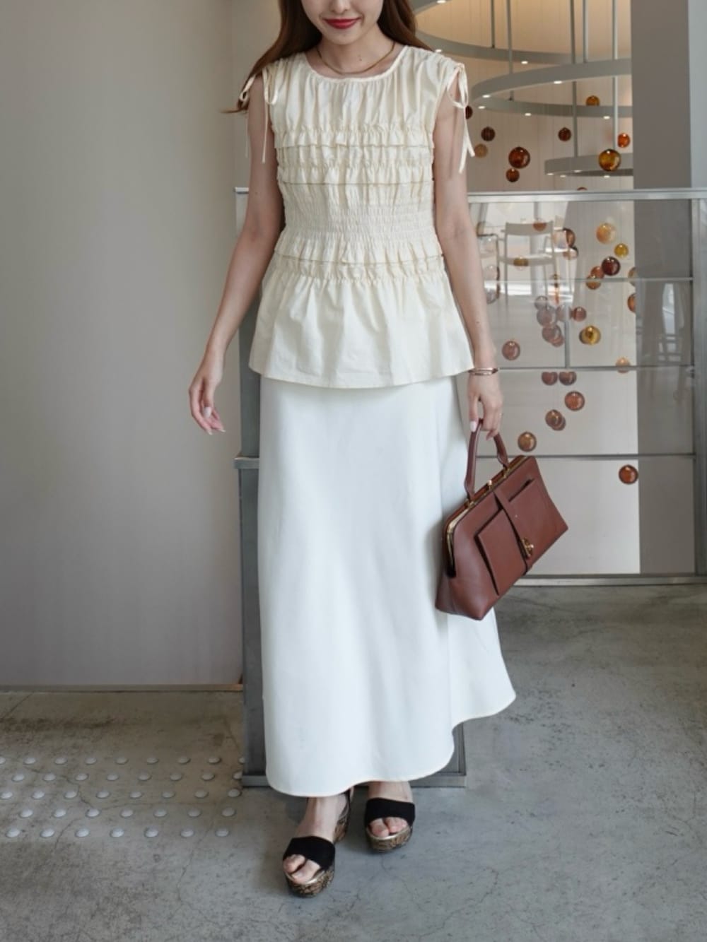 ブラック系のシャツ/ブラウス、ベージュ系のスカートを着用したレディースの夏コーディネートの2枚目の写真