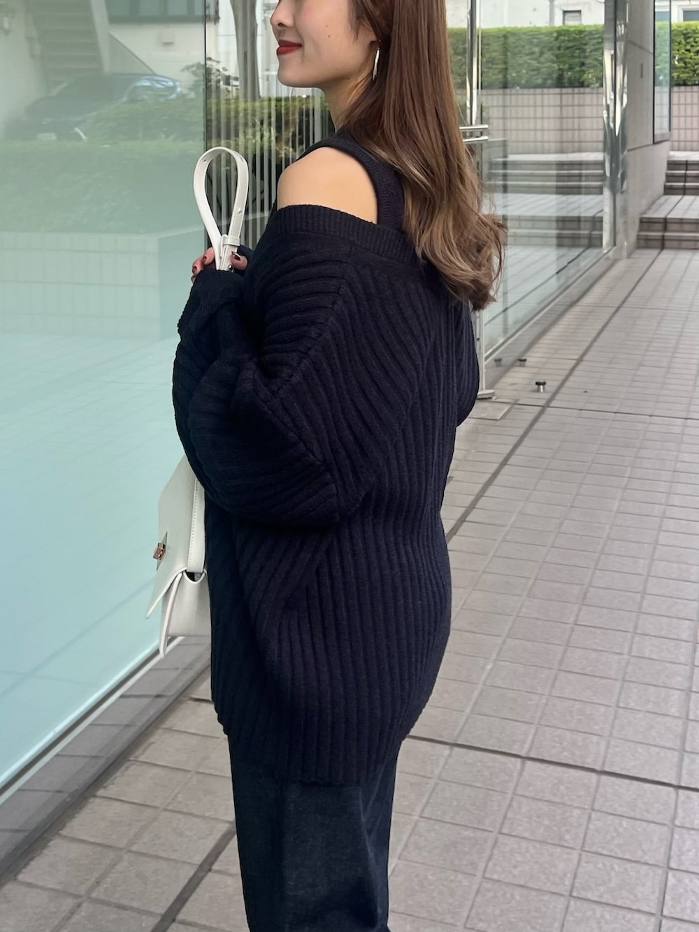 ホワイト系のニット/セーター、ブルー系のデニムパンツ、ホワイト系のショルダーバッグを着用したレディースの春コーディネートの5枚目の写真