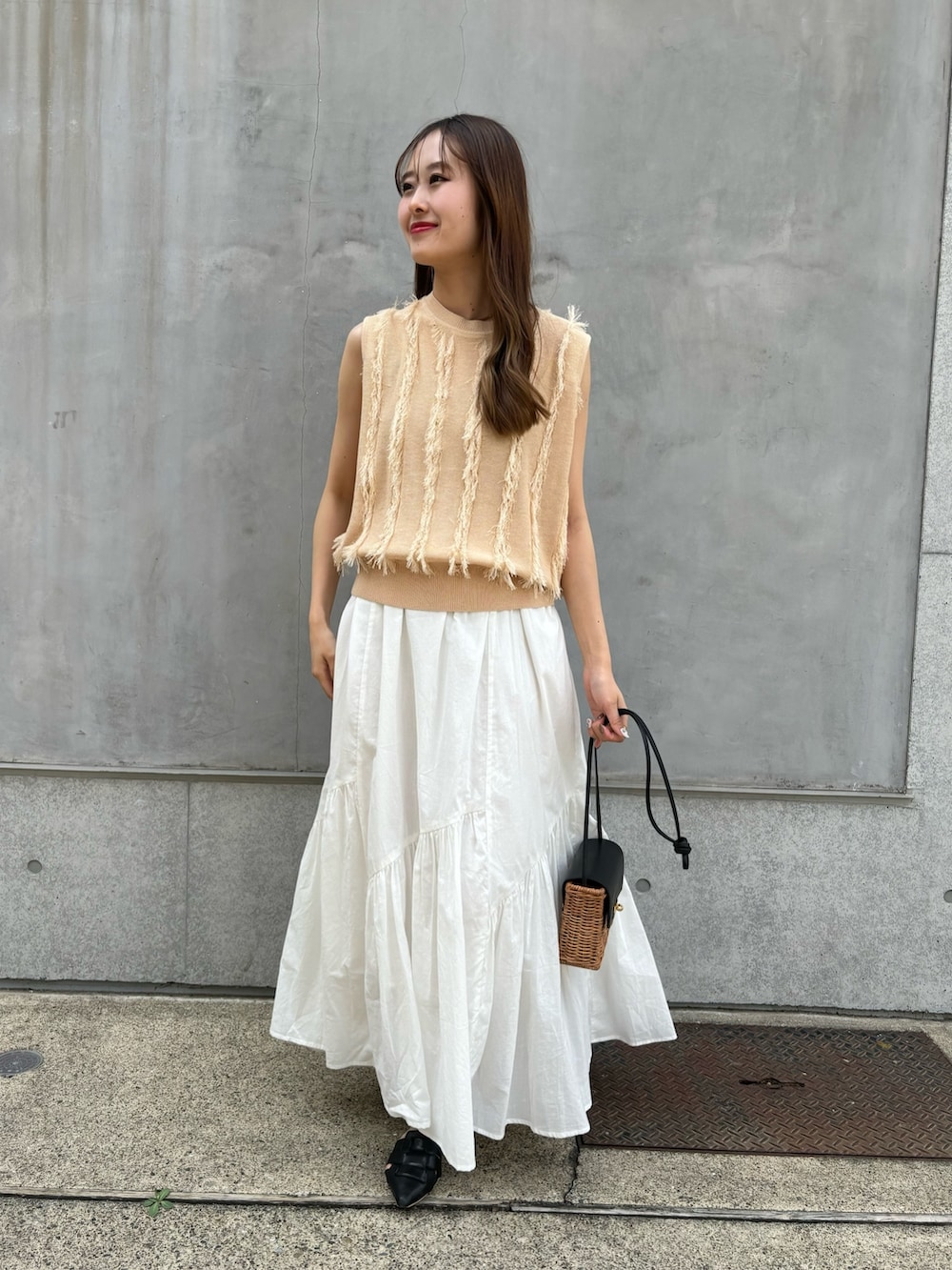 ベージュ系のニット/セーター、ホワイト系のスカート、ブラック系のショルダーバッグを着用したレディースの春コーディネートの2枚目の写真