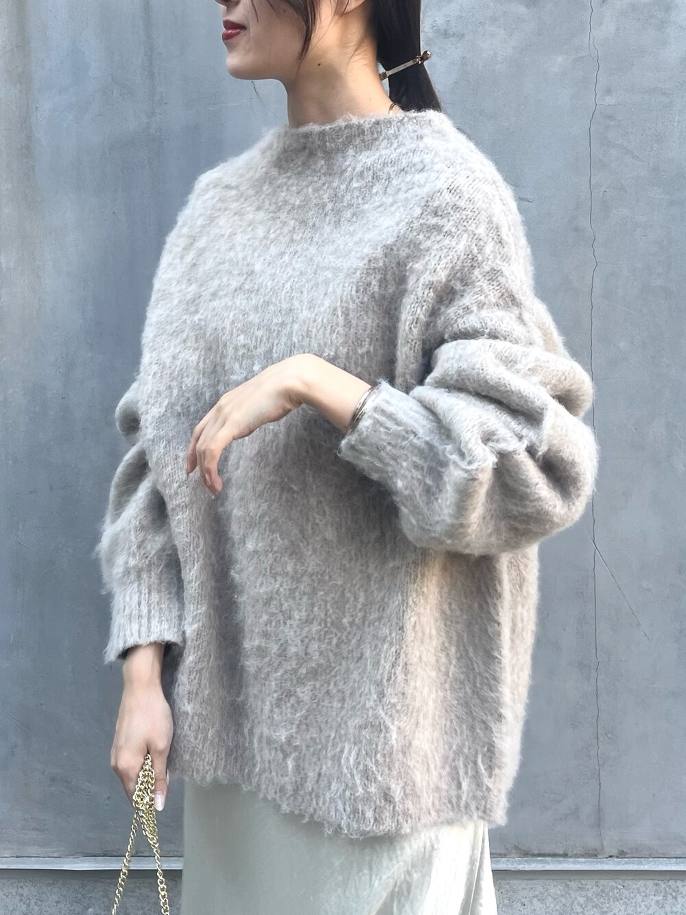 ベージュ系のニット/セーター、ホワイト系のスカート、ベージュ系のショルダーバッグを着用したレディースの冬コーディネートの5枚目の写真