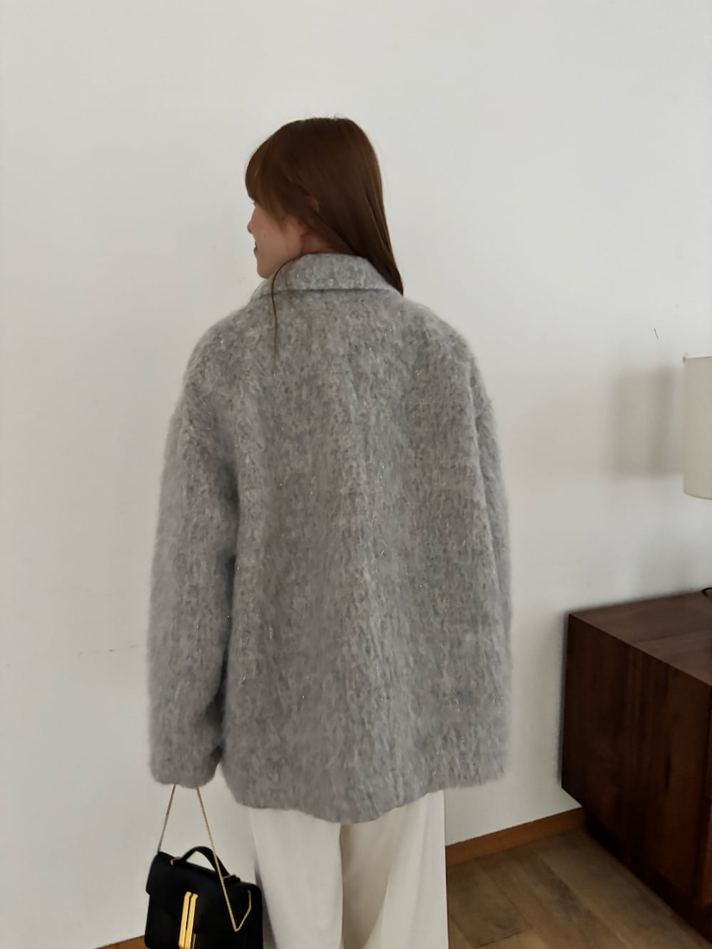 グレー系のピーコート、ホワイト系のスラックス、ブラック系のバッグを着用したレディースの秋コーディネートの5枚目の写真