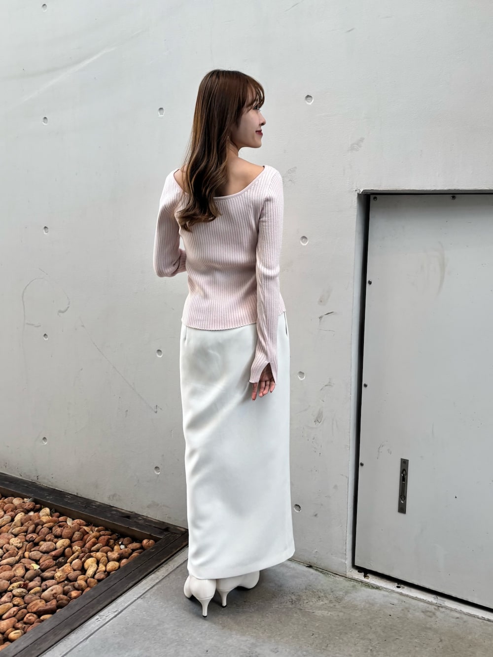 ピンク系のニット/セーター、ホワイト系のスカート、ホワイト系のブーツを着用したレディースの冬コーディネートの3枚目の写真
