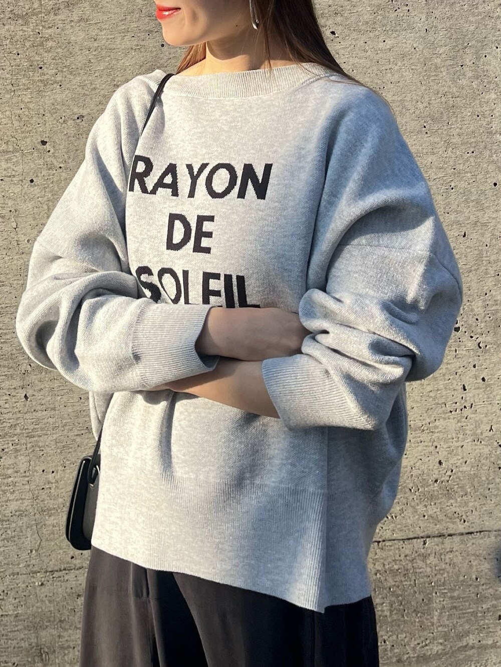 グレー系のニット/セーター、ブルー系のワンピース、ブラック系のショルダーバッグを着用したレディースの冬コーディネートの2枚目の写真