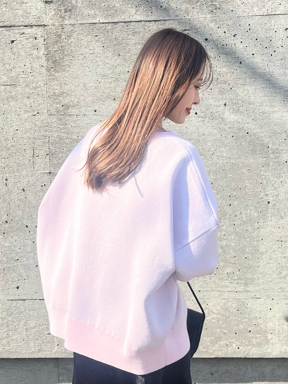 ピンク系のニット/セーター、ブラック系のスカート、ブラック系のショルダーバッグを着用したレディースの春コーディネートの3枚目の写真