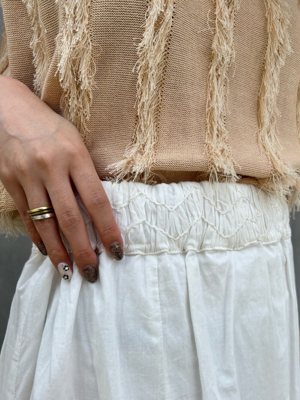 ベージュ系のニット/セーター、ホワイト系のスカート、ブラック系のショルダーバッグを着用したレディースの春コーディネートの7枚目の写真