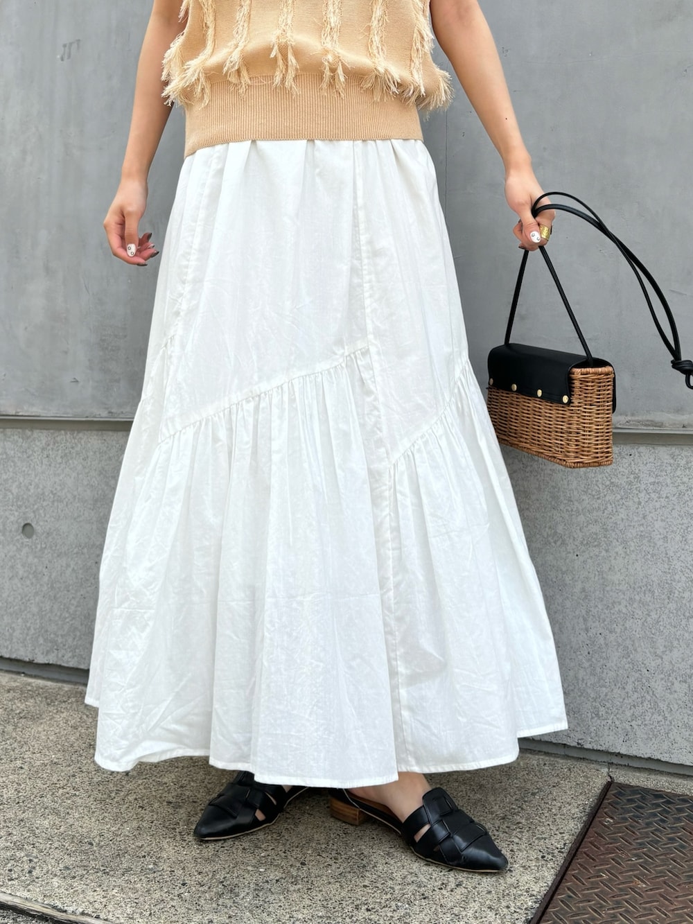 ベージュ系のニット/セーター、ホワイト系のスカート、ブラック系のショルダーバッグを着用したレディースの春コーディネートの6枚目の写真