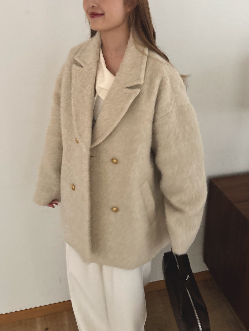 ベージュ系のピーコート、ホワイト系のスラックスを着用したレディースの秋コーディネートの3枚目の写真