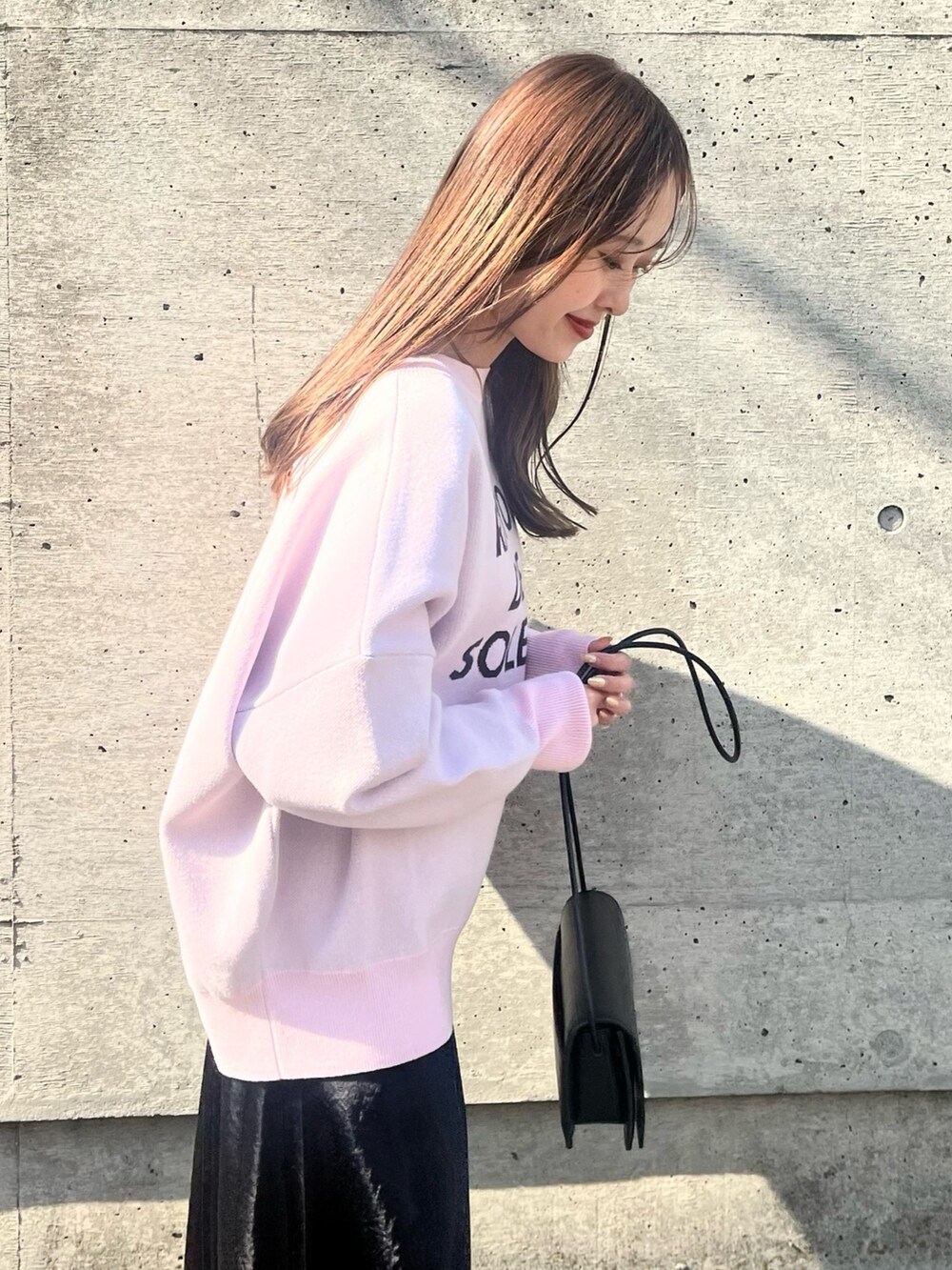 ピンク系のニット/セーター、ブラック系のスカート、ブラック系のショルダーバッグを着用したレディースの春コーディネートの4枚目の写真